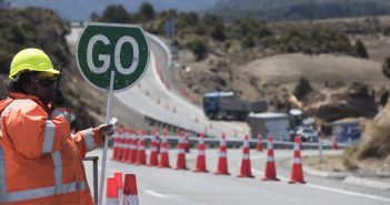 Construction worker holds up a "go" sign at roadworks